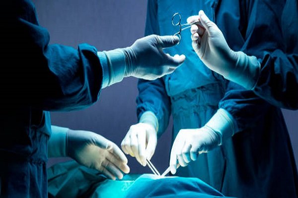 doctor and nurse medical team are performing surgical operation at emergency room in hospital. assistant hands out scissor and instruments to surgeons during operation.