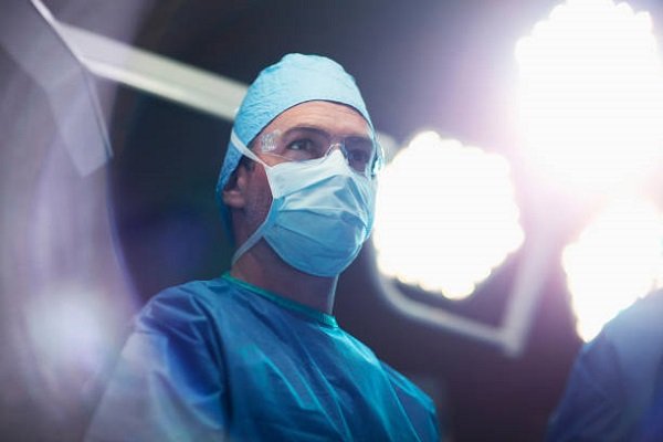 Portrait of Caucasian Middle Eastern multiracial ethnicity mature man medical doctor surgeon nurse in operating room in hospital with surgical light